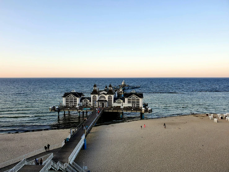 a pier sitting on top of a sandy beach next to the ocean, bauhaus, in the evening, profile image, multiple stories, jörmungandr