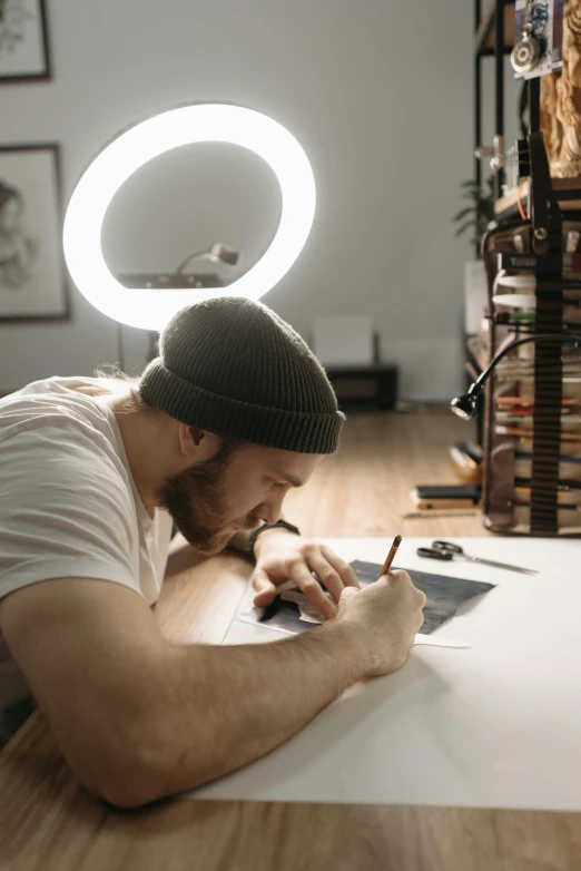 a man sitting at a table writing on a piece of paper, a drawing, by artist, pexels contest winner, studio lit, caleb worcester, instagram art, tattoo artist