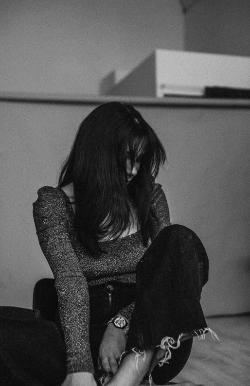 a black and white photo of a woman sitting on the floor, a black and white photo, inspired by Elsa Bleda, pexels, 'i'm so tired, girl with black hair, looking down, sittin