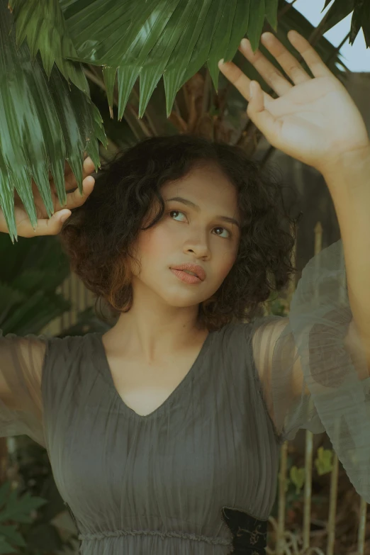 a woman standing in front of a palm tree, an album cover, inspired by Fernando Amorsolo, pexels contest winner, renaissance, curly and short top hair, actress, see - through, teenage girl