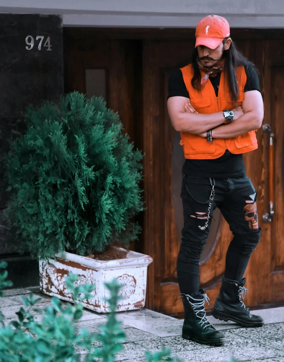 a man standing in front of a wooden door, an album cover, trending on pexels, orange safety vest, vitaly bulgarov, prideful look, full body with costume
