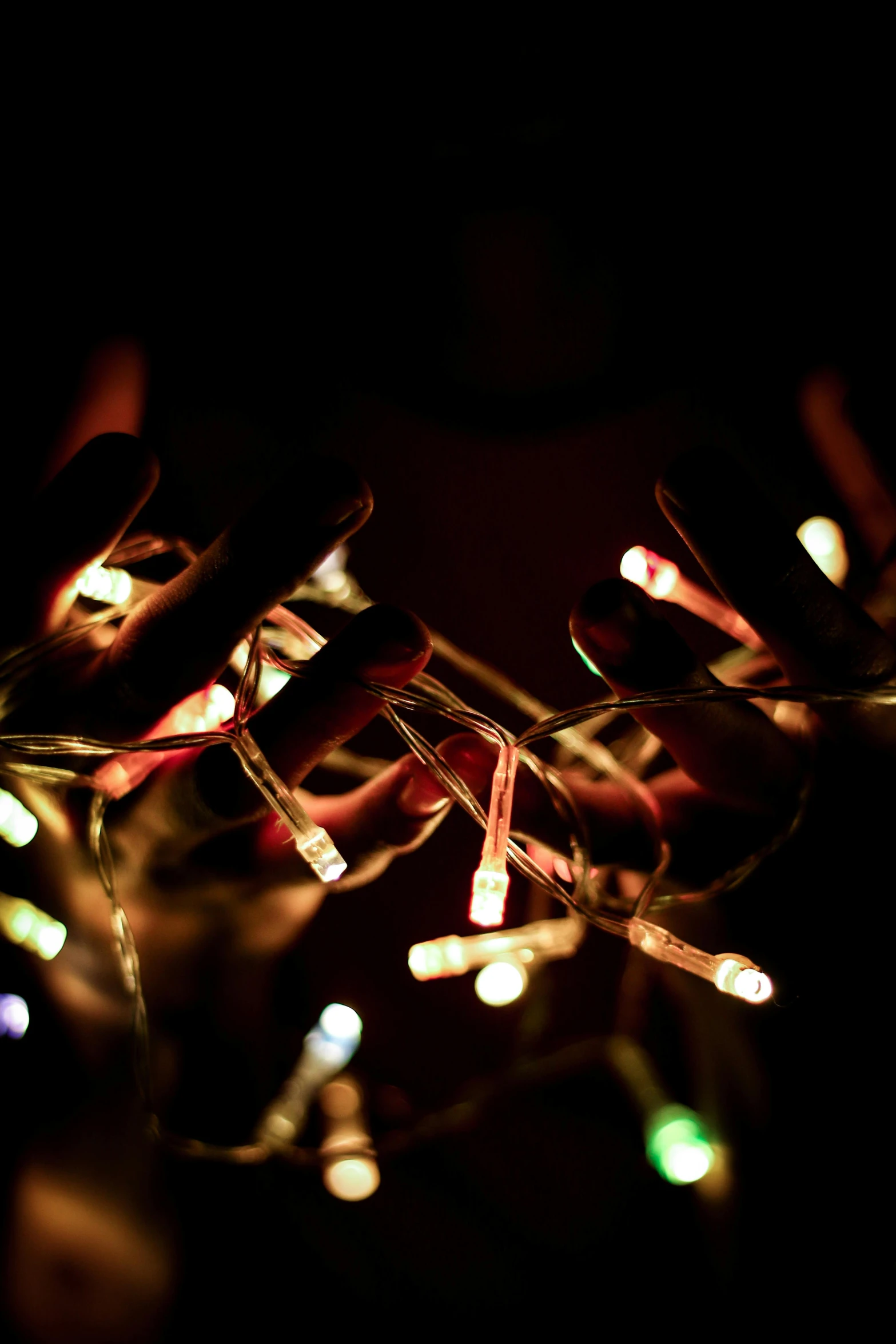 a close up of a string of lights in the dark, hands, holiday vibe, digital still, rectangle