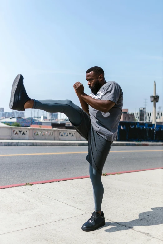 a man is doing a kick in the street, inspired by Ma Quan, pexels contest winner, happening, idris elba as james bond, standing on rooftop, fighting stance energy, thighs