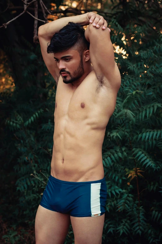 a shirtless man standing in front of a bush, inspired by Ludovit Fulla, pexels contest winner, sport bra and dark blue shorts, andres rios, asher duran, gif