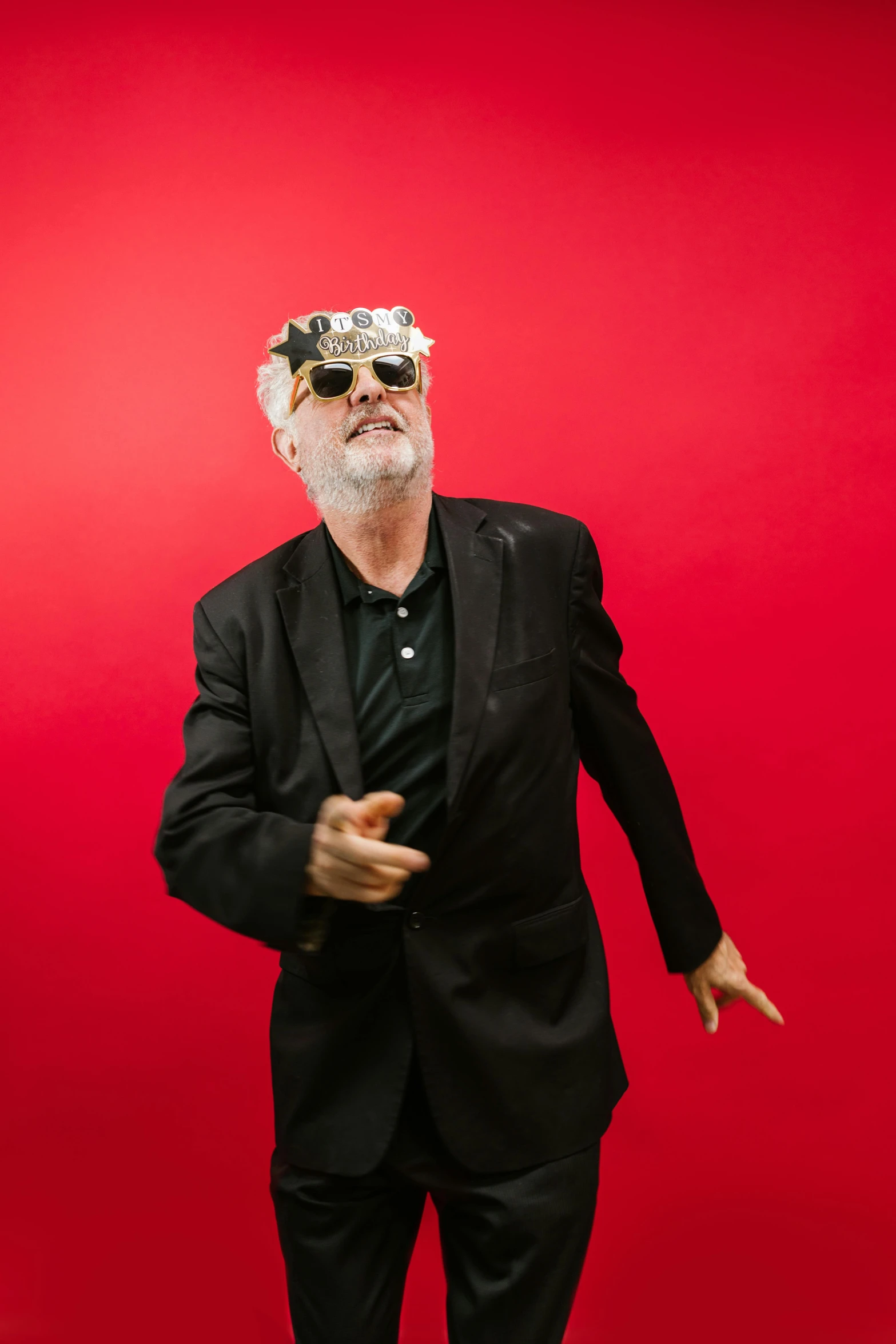a man in a suit and sunglasses on a red background, overalls and a white beard, in an action pose, wearing a party hat, bill stoneham