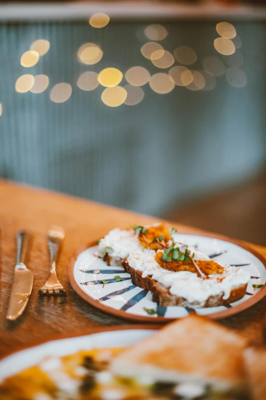 a wooden table topped with plates of food, by Carey Morris, pexels contest winner, renaissance, anamorphic bokeh, toast, orange and white color scheme, winter