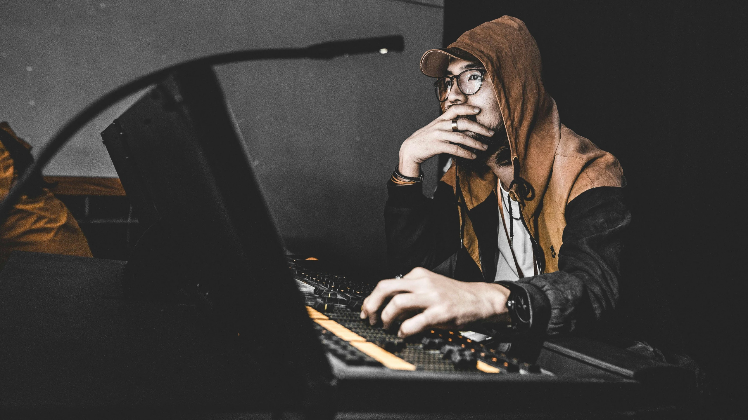 a man in a hoodie sitting in front of a keyboard, trending on pexels, mining, avatar image, cinematic outfit photo, maintenance photo