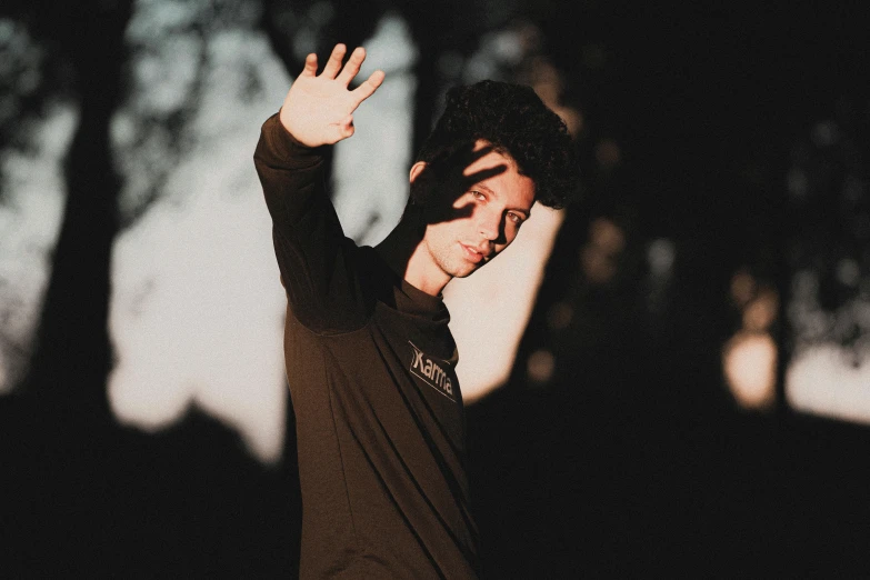 a man in a black shirt doing a trick on a skateboard, an album cover, pexels contest winner, holding his hands up to his face, portrait soft light, avatar image, zachary corzine