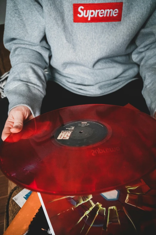 a person holding a red vinyl record in their hands, an album cover, inspired by Elsa Bleda, pexels, sitting down, inspect in inventory image, resin, red monochrome