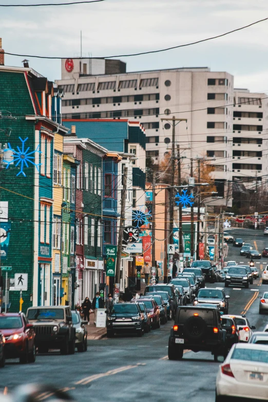 a street filled with lots of traffic next to tall buildings, inuit heritage, small town surrounding, colorful signs, holiday season