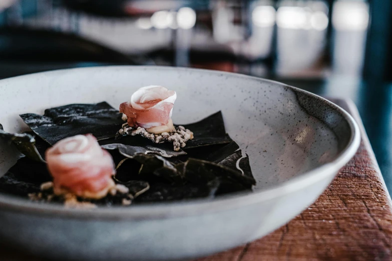 a bowl of food sitting on top of a wooden table, unsplash, mingei, back shark fin, charcoal and champagne, seaweed, sydney hanson