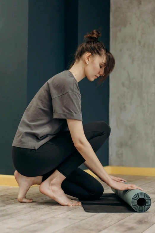 a woman kneeling on the floor with a yoga mat, renaissance, wheels, grey, square, high-quality photo