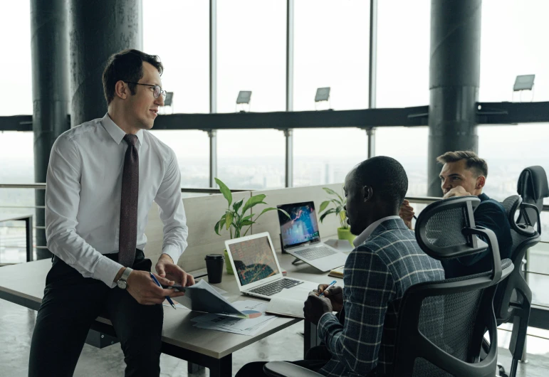 a group of people sitting around a table with laptops, by Carey Morris, pexels contest winner, set inside of office, lachlan bailey, calmly conversing 8k, portrait of tall