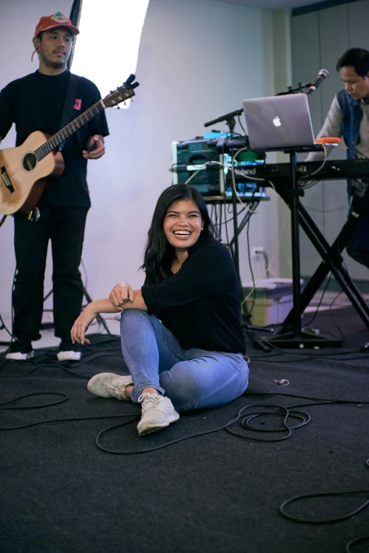 a woman sitting on the ground with a guitar, happening, smiling slightly, sitting in front of a microphone, joy ang, asher duran