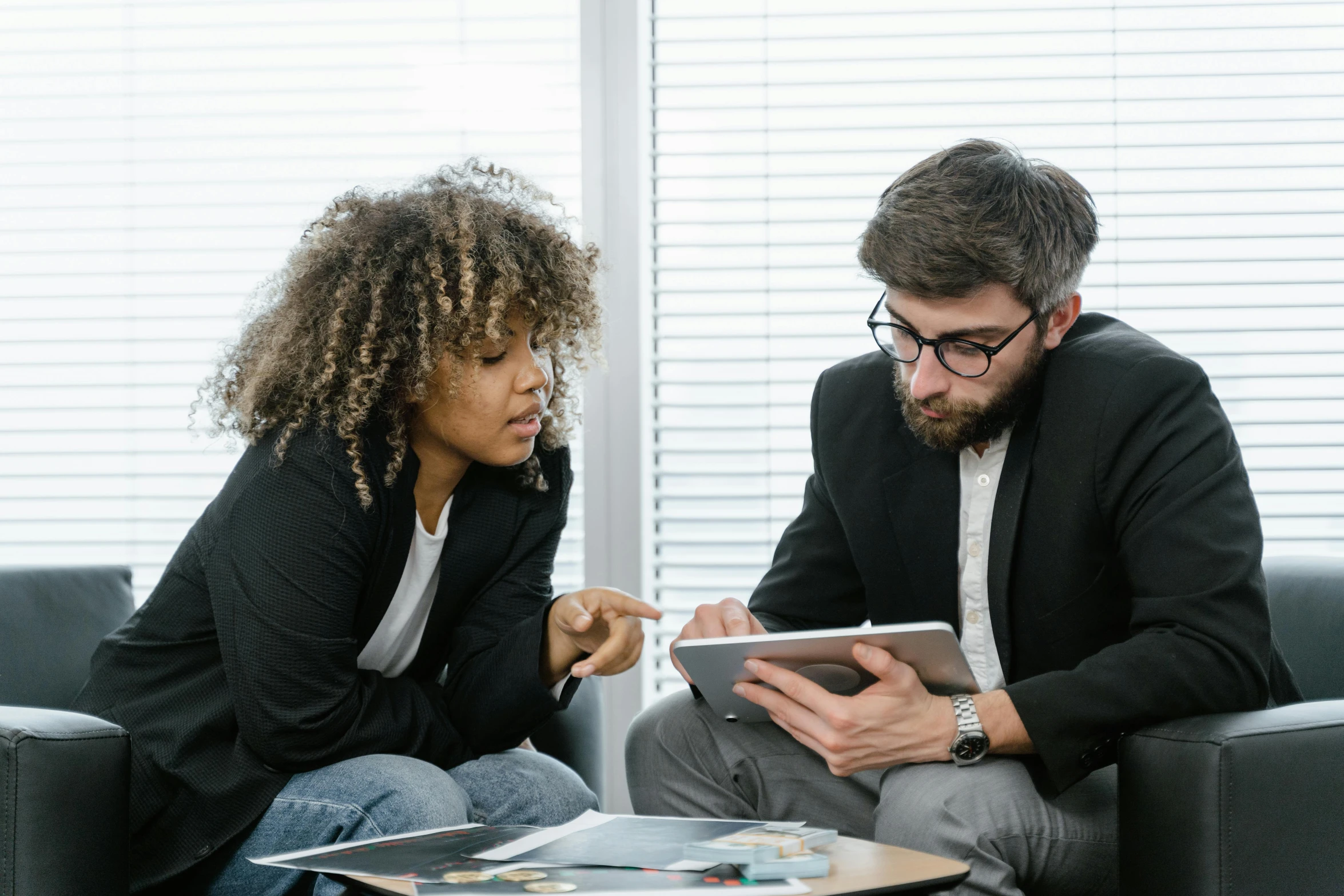 a man and woman sitting on a couch looking at a tablet, by Carey Morris, pexels contest winner, sat in an office, avatar image, teaching, with black