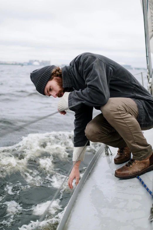 a man that is on a boat in the water, bending down slightly, a cold, scientific study, streetwear