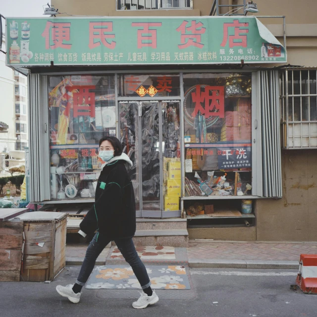 a woman walking down a street past a store, 中 元 节, girl wearing hoodie, sea - green and white clothes, album photo