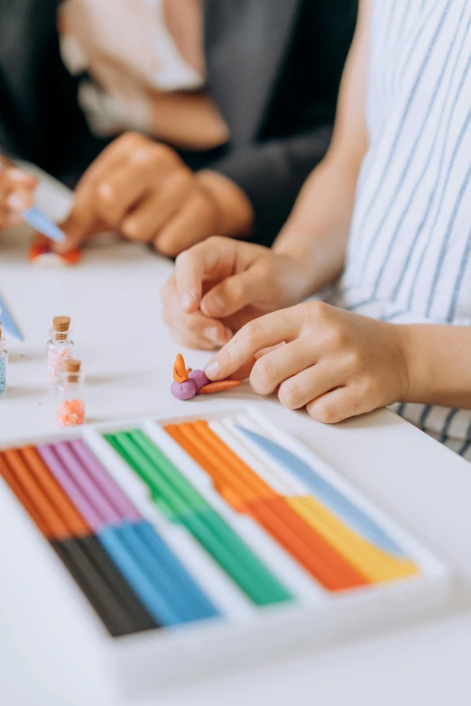 a group of people sitting at a table with pencils, pexels contest winner, crayon art, play - doh, subtle detailing, toy design, private school