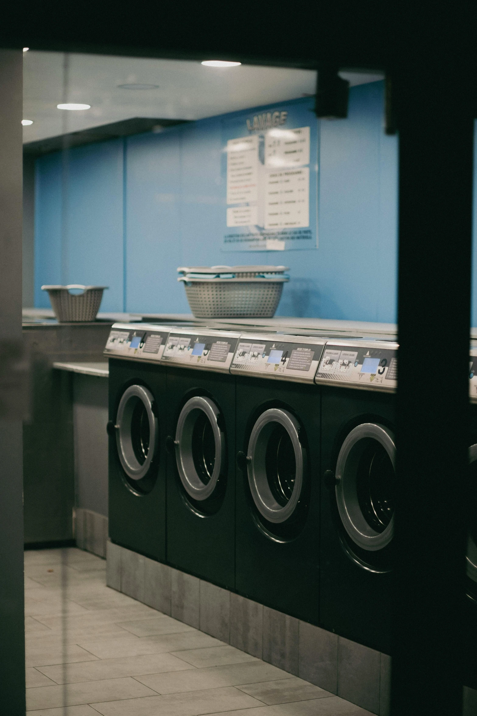 a row of washing machines sitting next to each other, a silk screen, unsplash, pitch black room, blue gray, ignant, ground level shot