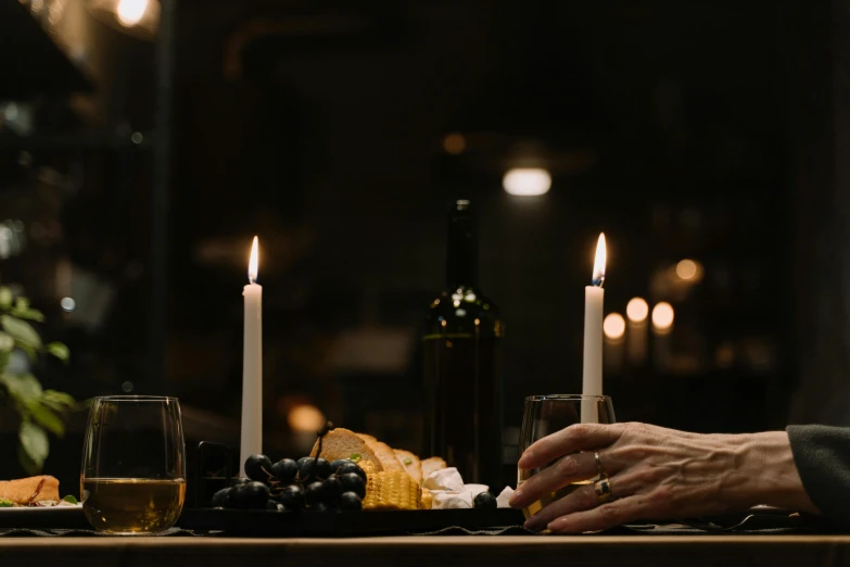 a couple of people that are sitting at a table, a still life, by Matt Cavotta, pexels contest winner, renaissance, white candles, mid night, back of hand on the table, themed after wine