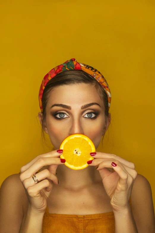 a woman holding an orange in front of her face, by Adam Marczyński, pexels contest winner, colors: yellow, square, food focus, sexy face