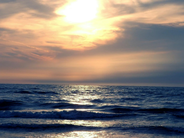 a person flying a kite on top of a beach, during a sunset, body of water, profile image, wavy water