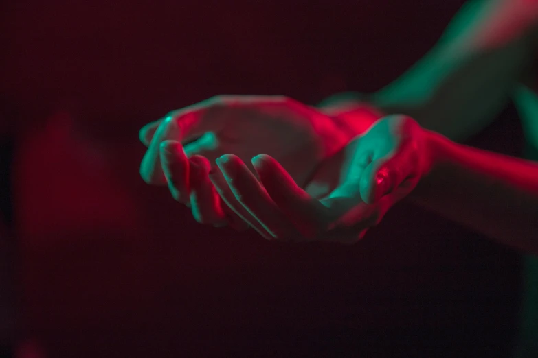 a close up of a person holding something in their hands, an album cover, inspired by Elsa Bleda, pexels contest winner, visual art, darkness aura red light, colours red and green, empty hands, psychedelic therapy