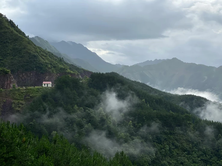 a white house sitting on top of a lush green hillside, by Daniel Lieske, unsplash contest winner, sumatraism, grey mist, sichuan, ( ( ( ( kauai ) ) ) ), view from a distance