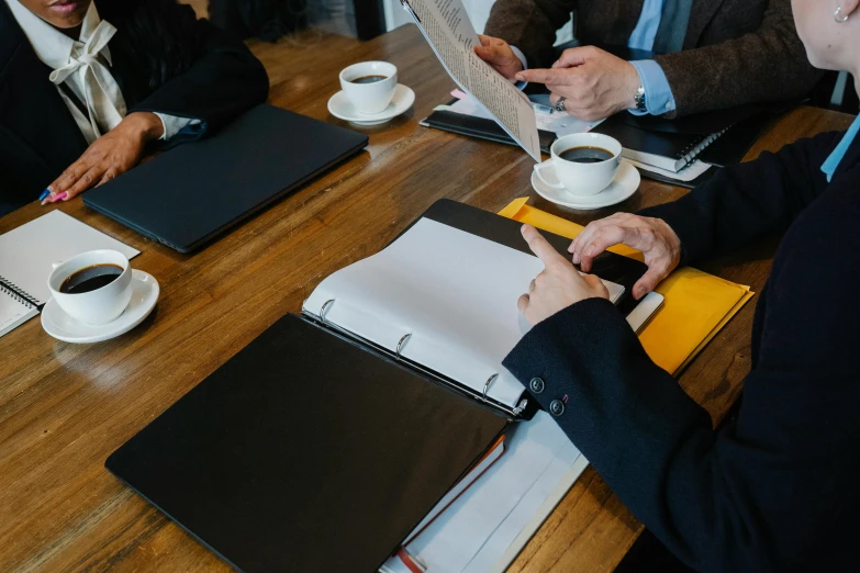 a group of people sitting around a wooden table, pexels contest winner, private press, wearing causal black suits, pen and paper, background image, maintenance