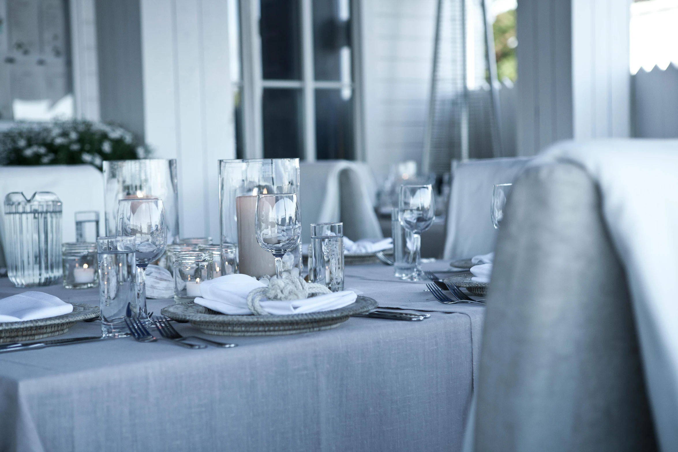 a table that has a bunch of place settings on it, by Helen Stevenson, unsplash, soft grey and blue natural light, candlelit restaurant table, linen, white and silver