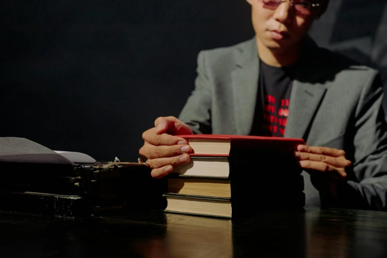 a man sitting at a table holding a book, with professional lighting, darren quach, stacked image, **cinematic