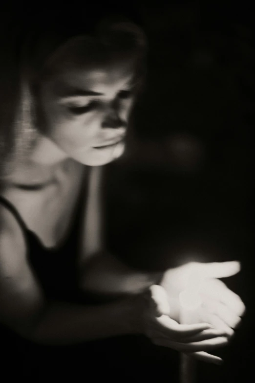 a black and white photo of a woman holding a flower, inspired by Roy DeCarava, unsplash, art photography, candlelight, checking her cell phone, emanating magic from her palms, medium format. soft light