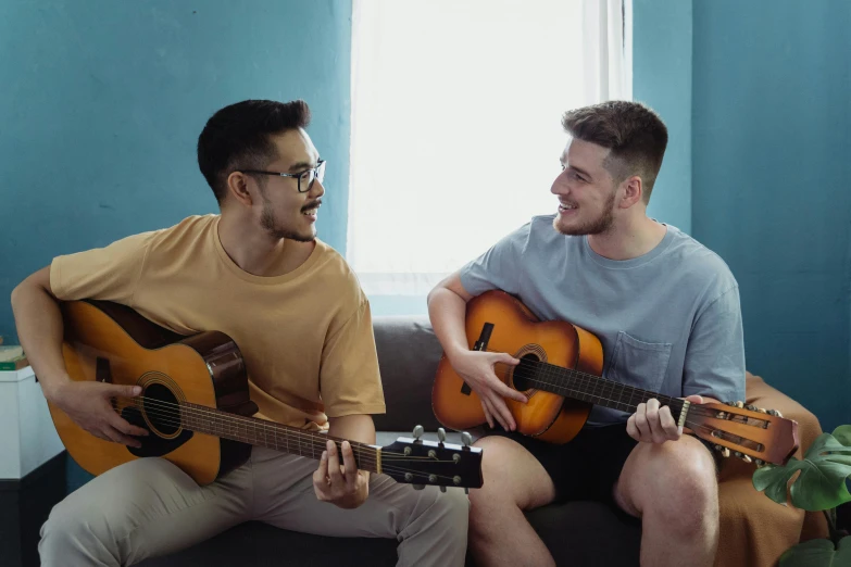 two men sitting on a couch playing guitars, inspired by Wang Duo, pexels contest winner, avatar image, lgbt, college students, background image