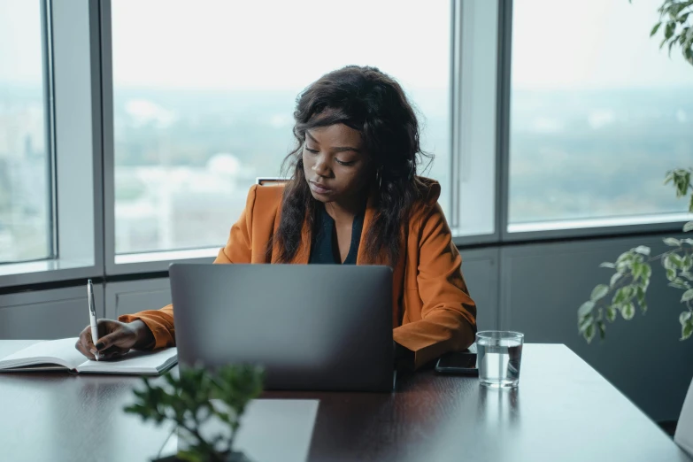 a woman sitting at a table working on a laptop, pexels contest winner, black female, official screenshot, coworkers, multiple stories