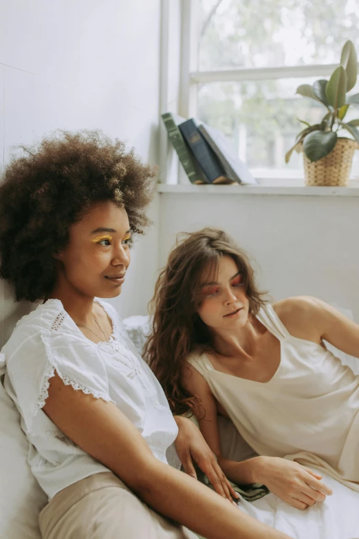 a couple of women sitting on top of a bed, trending on pexels, renaissance, with textured hair and skin, sitting on the couch, her friend, slightly minimal