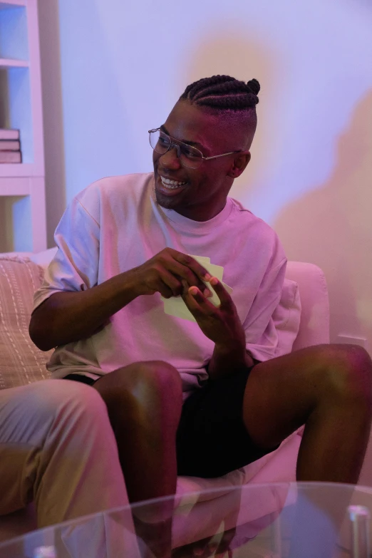 a man sitting on a couch in a living room, inspired by Barthélemy Menn, pexels contest winner, playboi carti portrait, manically laughing, shaved sides, with glasses on