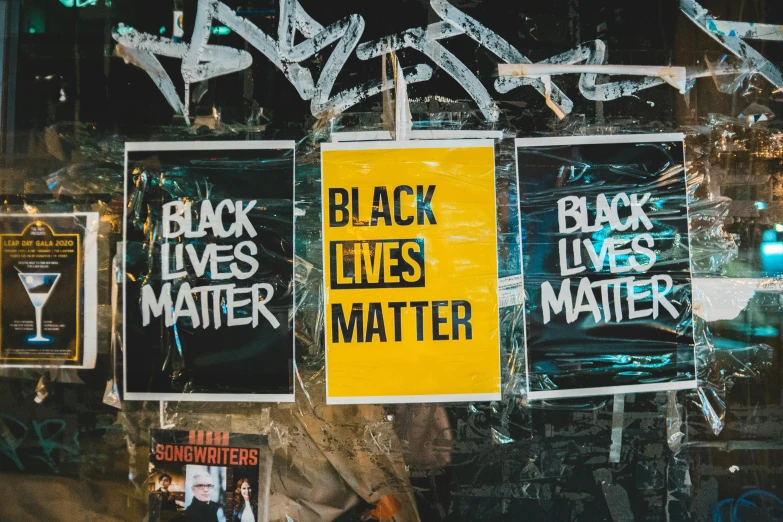 a group of posters hanging on the side of a building, trending on unsplash, black arts movement, background image, protest, black. yellow, heath clifford