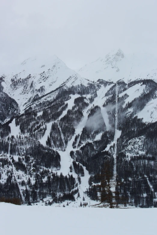 a man riding skis down a snow covered slope, an album cover, pexels contest winner, “ aerial view of a mountain, grey sky, complex and intricate, ominous! landscape of north bend