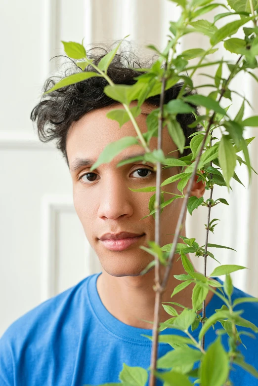 a close up of a person holding a plant, an album cover, inspired by Carlos Berlanga, young man with beautiful face, light skin, looking to camera, official government photo