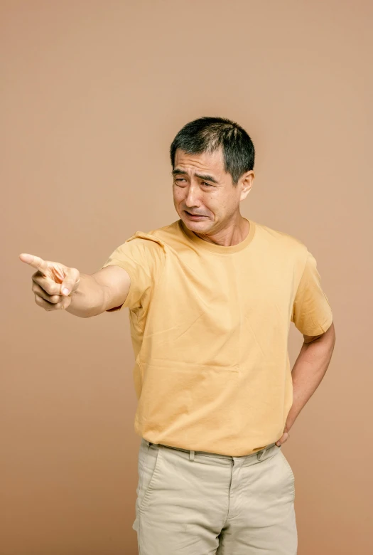 a man in a yellow shirt pointing at something, trending on pexels, dau-al-set, ethnicity : japanese, mature male, ouch, brown clothes