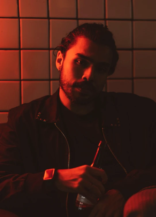 a man sitting on a couch in a dimly lit room, an album cover, by Alejandro Obregón, trending on pexels, serial art, a portrait of rahul kohli, red neon, post malone, close up portrait shot