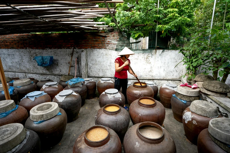 a woman standing in a room filled with pots, rice, bao phan, avatar image