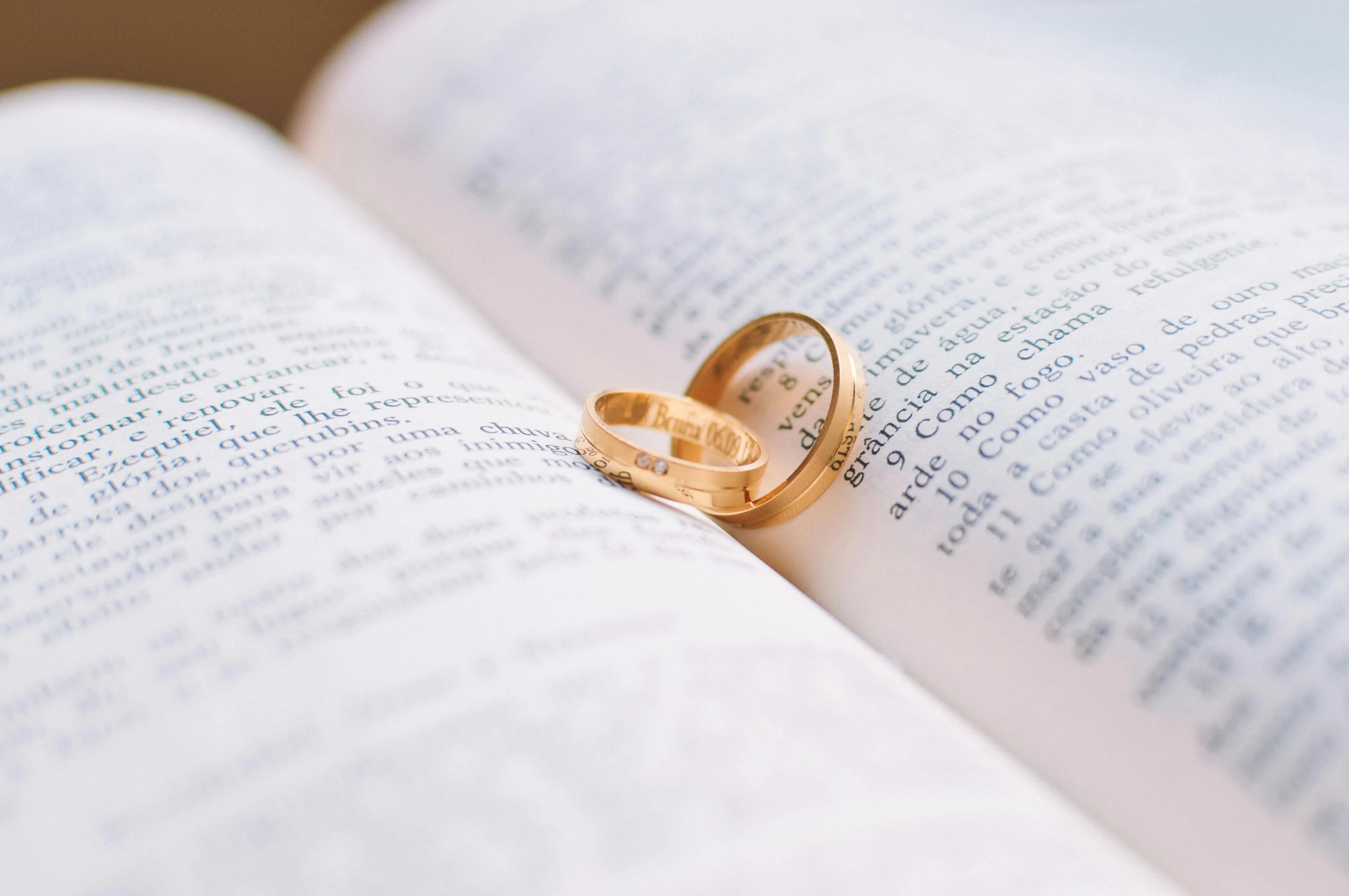 a couple of wedding rings sitting on top of an open book, pexels, gold plated, book title visible, thumbnail, instagram post