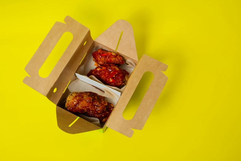 a box of chicken wings on a yellow background, pexels, dau-al-set, male and female, reverse, stuffed, sauce