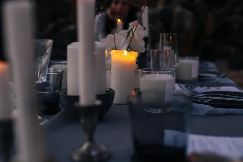 a group of people sitting at a table with candles, by Carey Morris, unsplash, renaissance, charcoal and champagne, soft outdoor light, linen, close-up photo