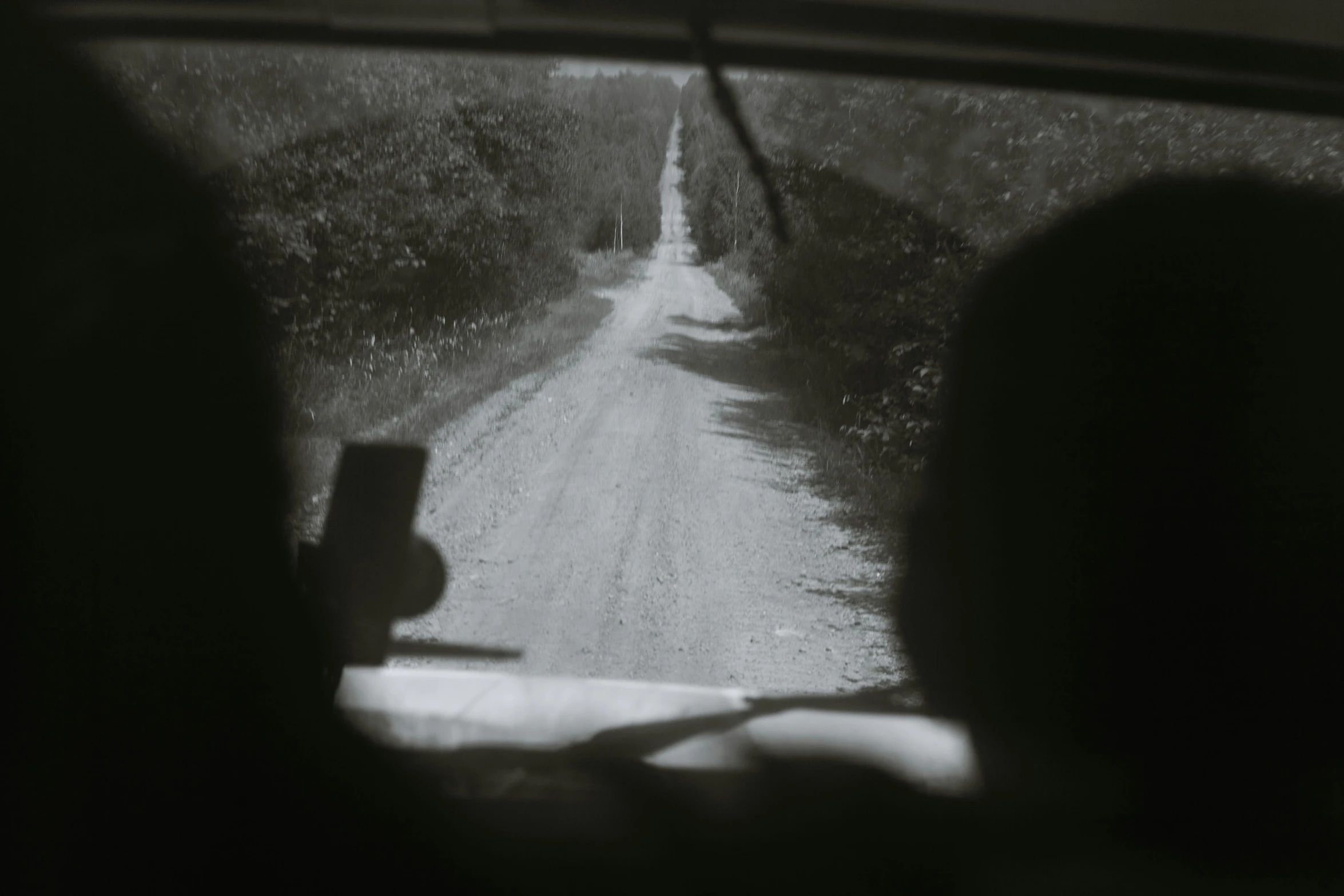 a black and white photo of a dirt road, inspired by Bert Hardy, pexels contest winner, inside of a car, vhs footage still, colour photograph, rinko kawauchi