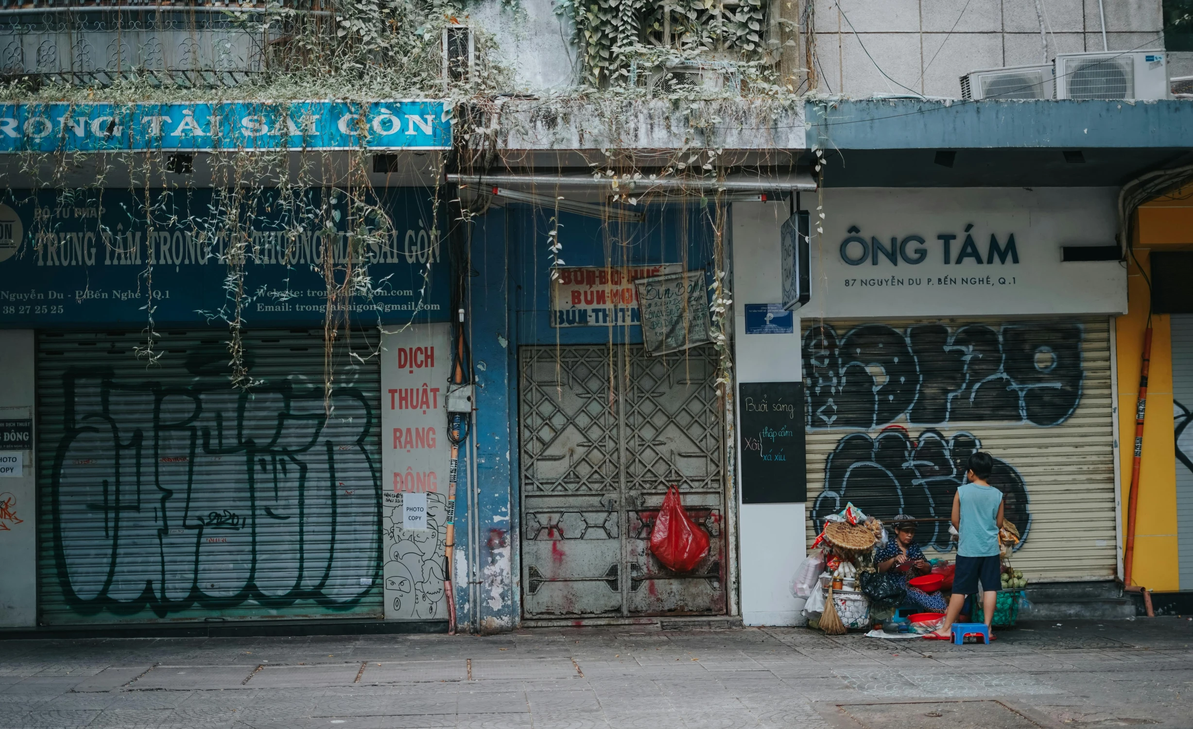 a couple of people standing in front of a building, graffiti, vietnamese woman, belongings strewn about, doors, unsplash photo contest winner