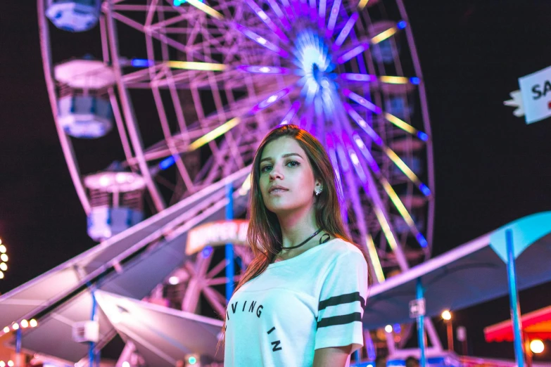 a woman standing in front of a ferris wheel, a portrait, pexels contest winner, violet and aqua neon lights, dressed in a white t shirt, california;, portrait sophie mudd