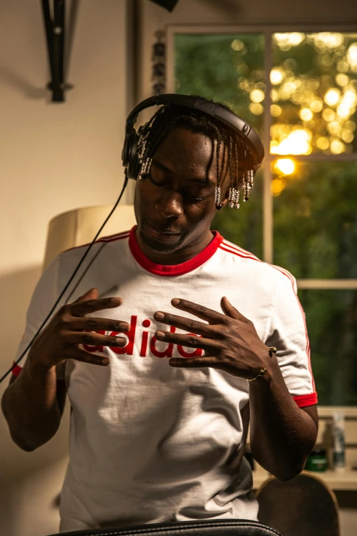 a man sitting in a chair with headphones on, an album cover, trending on pexels, happening, wearing adidas clothing, adut akech, headshot profile picture, programming