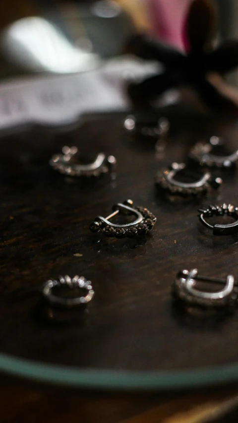 a bunch of rings sitting on top of a wooden table, metal teeth, thumbnail, intricate details in the frames, in a workshop